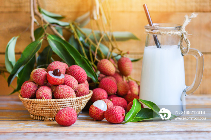 Fresh lychee drink and slice peeled with green leaves harvest in basket from tree tropical fruit summer in Thailand - Lychee juice on wooden table