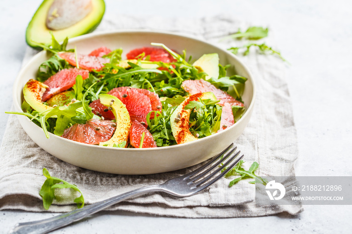 Avocado and grapefruit salad in a white plate on a white background.