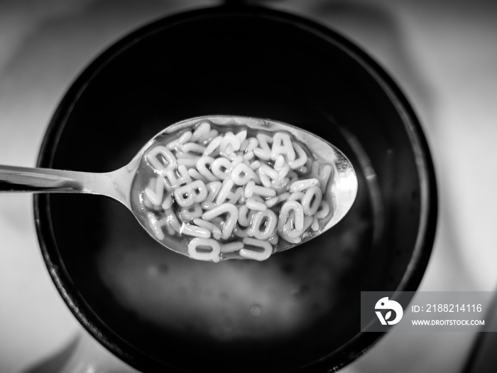 Image of black and white alphabet noodels soup with spoon