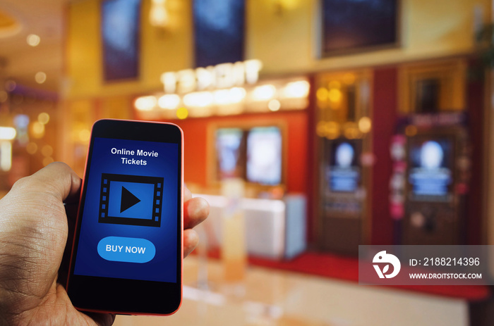 hand using mobile smart phone to buy cinema tickets with blurred image of ticket sales counter at movie theater with graphic icon diagram, reserved seating, online booking and payment concept