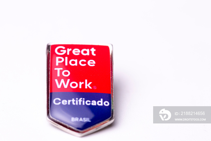 Button with the text Great Place To Work written on a solid white surface casting a short shadow on the background. TRANSLATION: ’CERTIFIED. BRAZIL’