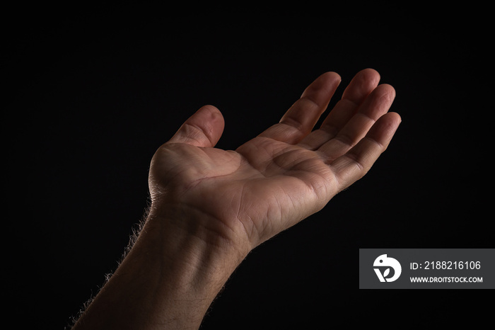 Left wrinkled palm asking for help on a black background.