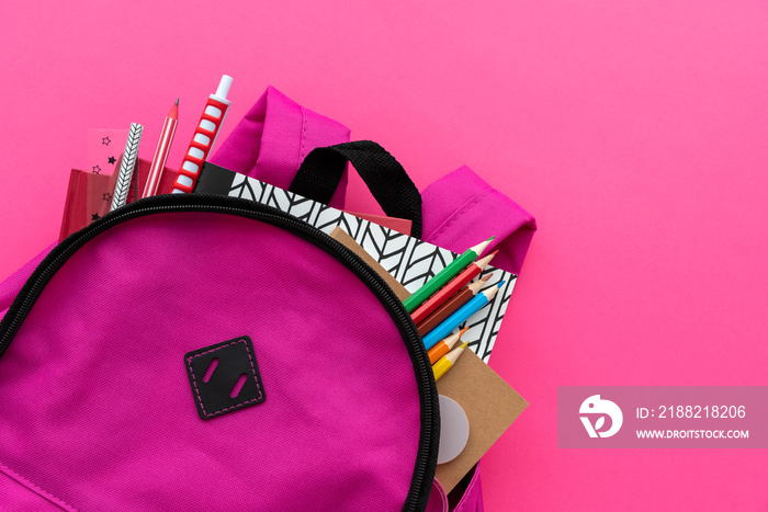 Back to school concept. Backpack with school supplies on pink background. Top view. Copy space