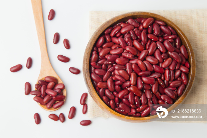 Red beans in wooden bowl and spoon putting on linen and white background.