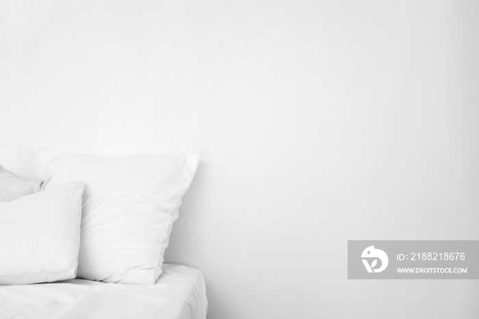 Soft pillows on bed near white wall