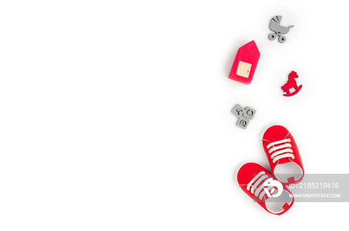 Baby shoes and wooden toys on white background with copy space