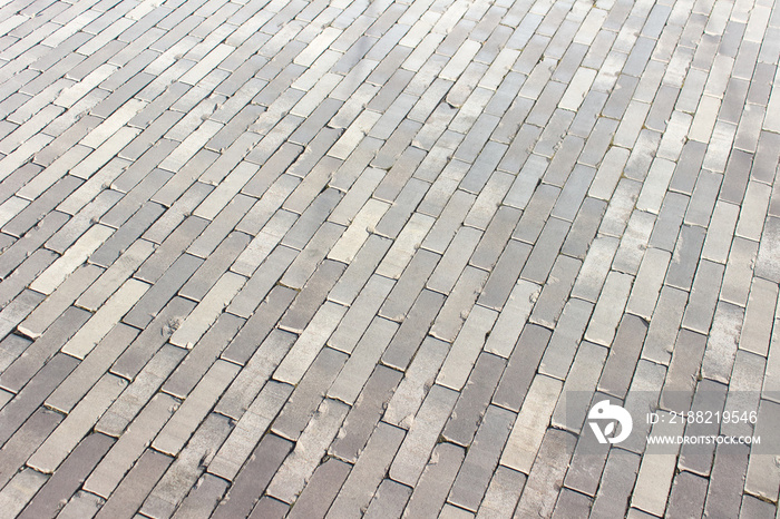 Texture of pedestrian walkway pavement with diagonal long rectangle gray bricks.