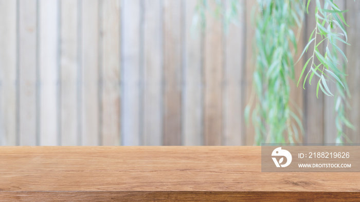 Empty wood table top and blurred wooden wall in garden background with Green leaves - can used for display or montage your products.