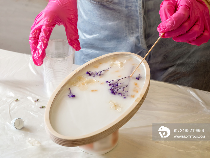 The art process of pouring epoxy resin into a wooden toy. Technology process of creating a painting in style resin art, works with epoxy in studio, makes a wooden stand with the image. Close up.