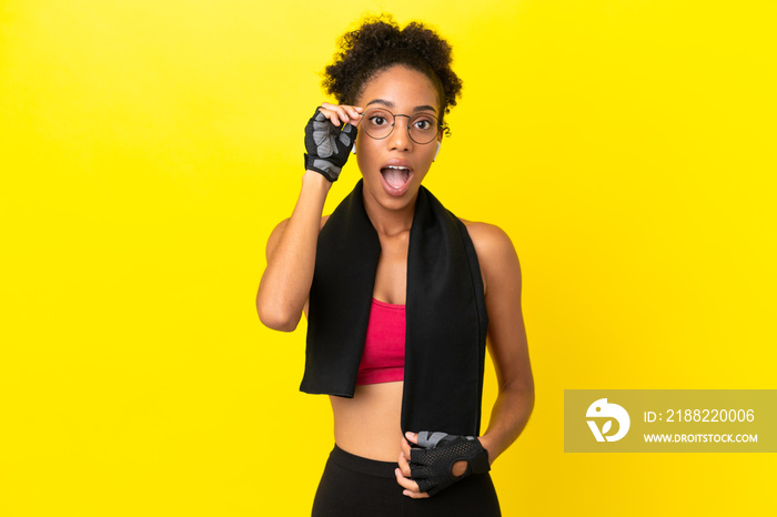 Young African sport woman isolated on yellow background with glasses and surprised