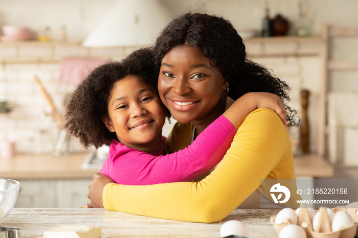 Mother’s Day Concept. Portrait Of Black Mom And Daughter Embracing In Kitchen