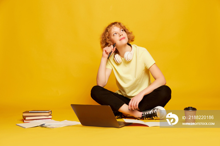 Portrait of young smiling girl, student in white t-shirt with laptop isolated on yellow color background. Concept of beauty, fashion, emotions, studying