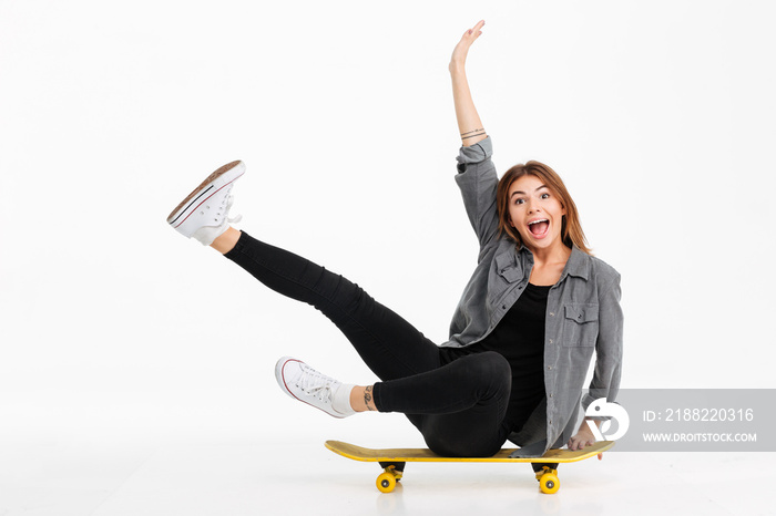 Portrait of a funny crazy girl sitting on a skateboard