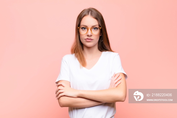 young red head woman feeling displeased and disappointed, looking serious, annoyed and angry with crossed arms against flat wall