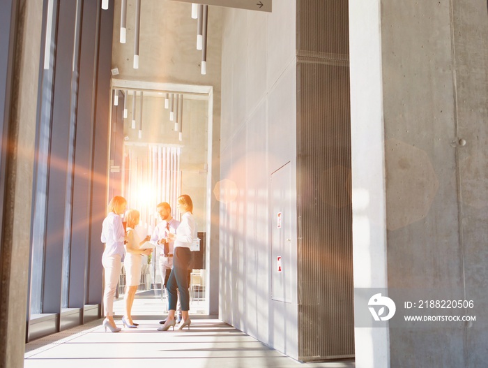 Business people brainstorming in office hall with yellow lens flare in background