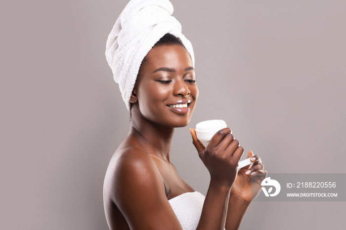 Young beautiful black woman holding jar of moisturizing face cream