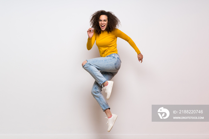 Dominican woman with curly hair jumping over isolated white background