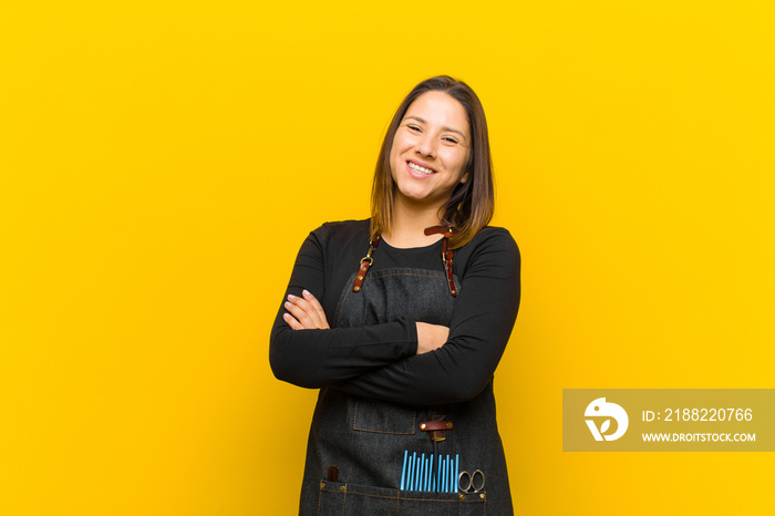 hairdresser woman laughing happily with arms crossed, with a relaxed, positive and satisfied pose against orange background