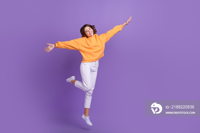 Full body photo of active overjoyed person jumping raise fists isolated on violet color background