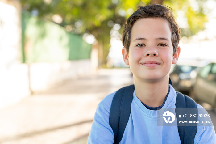 Close up portrait of cute boy with backpack outside of school.