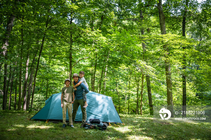 Air Force service member sets up a tent with his sons on  a backpacking trip.