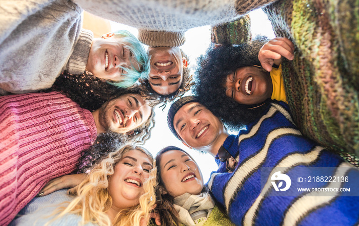 Diverse group of young friends embrace in a joyful circle, all smiling looking the camera. Multiethnic group of friends having fun together.