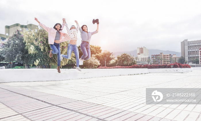 Young asian women jumping outdoor - Happy people friends having fun in urban city park - Generation z, youth, young people lifestyle concept