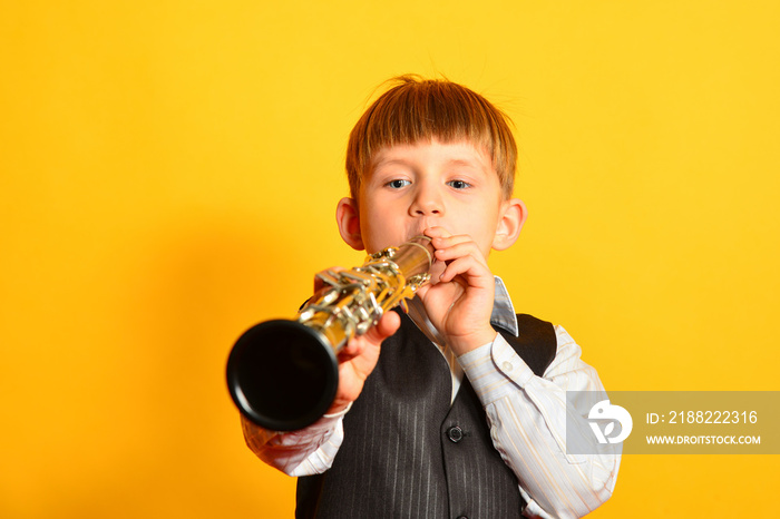 A little boy in a suit plays the clarinet