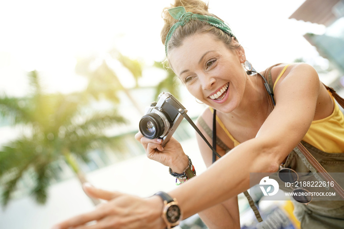 Stylish young woman taking photos with vintage camera in urban setting