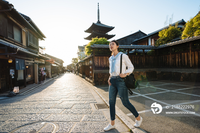 low angle and full length asian girl backpacker is gazing into the distance while wandering around at Yasaka dori near Hokanji Temple in Kyoto, japan at dusk.