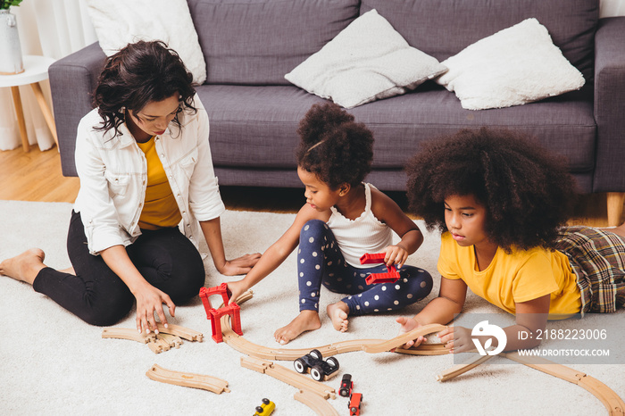 Mother parent playing with children learning to solve puzzle toy at home apartment. Nanny looking or childcare at living room black people.