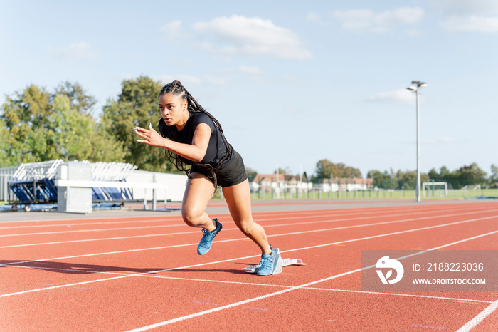 Female athlete sprinting off starting line at stadium