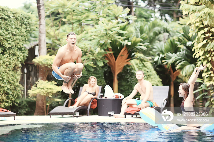 friends have fun in the summer pool at the hotel / cheerful company of young friends of men and women in summer swim in the pool on vacation hotel