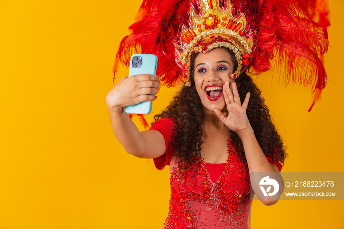 Young african woman in samba outfit at carnival enjoying the distance on cell phone.