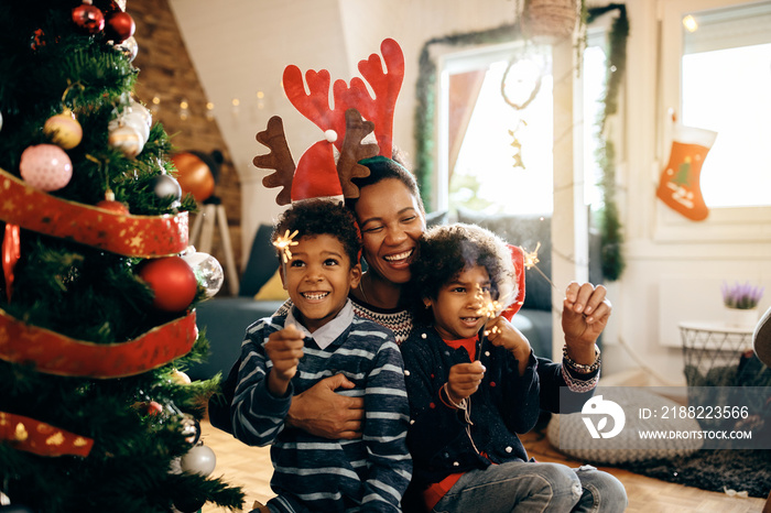 Joyful black family having fun with sparklers while celebrating Christmas at home.