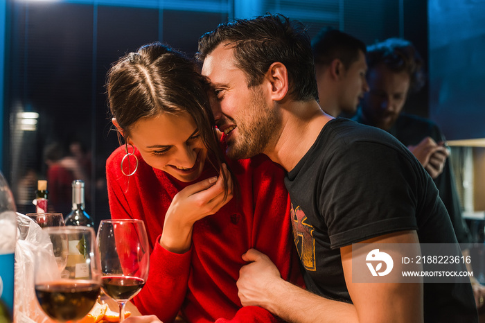 Beautiful couple laugh on home party and drinking red wine