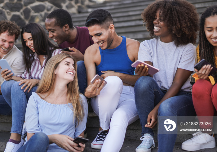 Group of diverse people enjoy day together outdoor - Young multiracial friends using mobile phone in the city