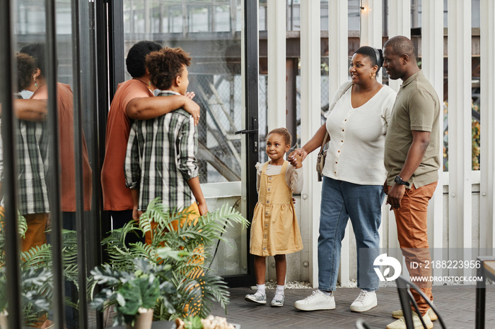 Full length portrait of happy multi-generational family chatting during gathering outdoors at terrace