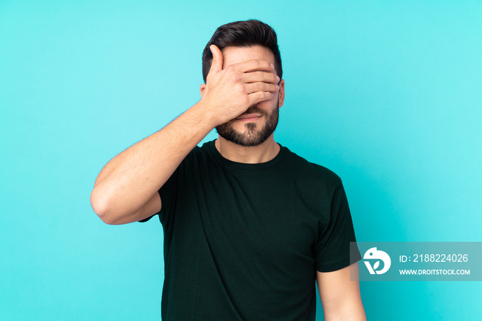 Caucasian handsome man isolated on blue background covering eyes by hands. Do not want to see something