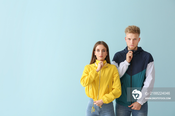 Young couple in stylish sportswear on color background