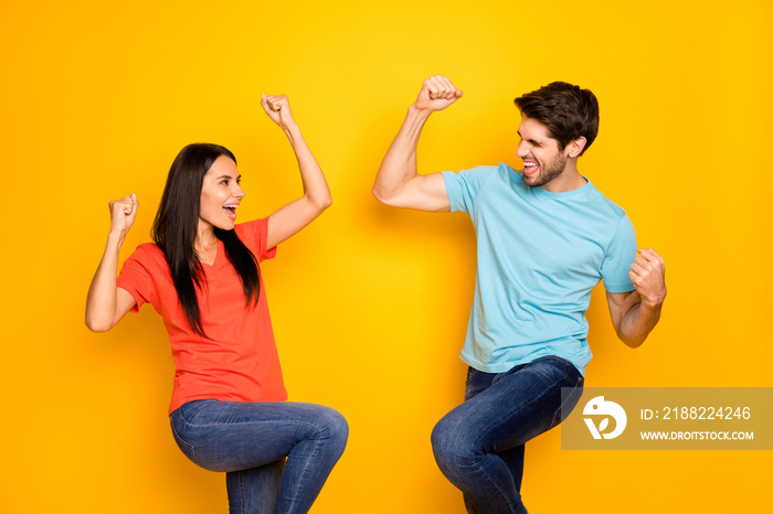 Photo of funny two people guy lady celebrating favorite football team winning raising fists rejoicing wear casual blue orange t-shirts jeans isolated yellow color background