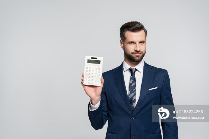 brunette economist showing calculator and smiling at camera isolated on grey.