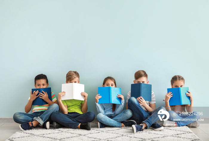 Cute little children with books on color background