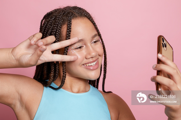 Studio shot of smiling girl with braids taking selfie