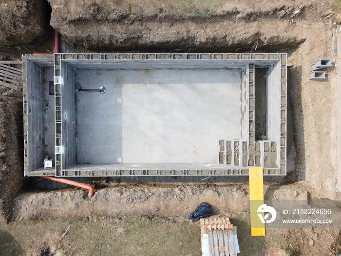 aerial drone shot of pool construction site, form blocks being filled with concrete