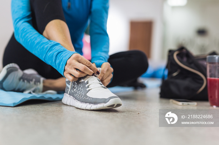 Woman tying shoelace before training in gym