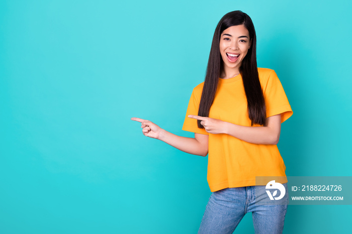 Photo of cute brunette long hairdo lady indicate promo wear orange t-shirt jeans isolated on teal color background