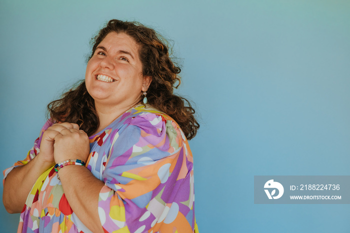 plus size woman looking up and smiling on blue background