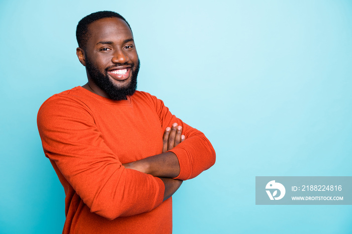 Photo of attractive dark skin business guy toothy beaming smiling in positive mood holding arms crossed wear casual orange pullover isolated blue color background