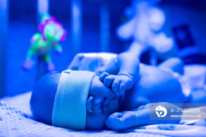 Newborn having a treatment for jaundice under ultraviolet light, Baby has high level of bilirubin, laying under blue light to reduce jaundice level. Safe medical procedures